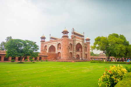 Agra, India - September 20, 2017: Unidentified people at the enter of a Great gate, Darwaza-i rauza, main entrance to the tomb walking near close to a huge green tree, UNESCO World Heritage Site, Agra, Uttar Pradesh, India.のeditorial素材