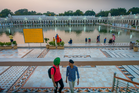 DELHI, INDIA - SEPTEMBER 19, 2017: Unidentified people walking upstairs and dowstairs, while other are swimming and washing their heads as lucky in the pond in the Famous Sikh gurdwara Golden Temple Harmandir Sahib in Indiaのeditorial素材