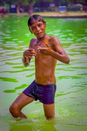 Delhi, India - September 16, 2017: Close up of unidentified smiling indian boy looking at camera, while he is inside of the pond, in Delhiのeditorial素材