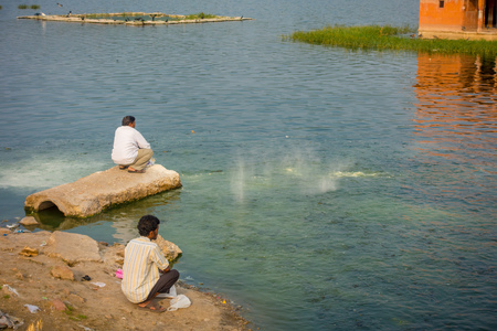 JAIPUR, INDIA - SEPTEMBER 20, 2017: Unidentified men enjoying in the border of the lake the beautiful Jal Mahal Water Palace on Man Sagar Lake in Jaipur, Rajasthan, Indiaのeditorial素材