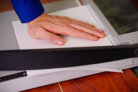 Close up of hand man over the guillotine, working on the guillotine, cutting paperの写真素材