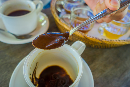 Hand adding with a spoon a Kopi Luwak Coffee from plantation in Bali, Indonesia, on wooden backgroundの写真素材
