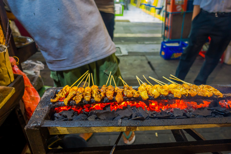 Street barbecue with meat skewers sizzling, very hot fire burning and man preparing food.の写真素材