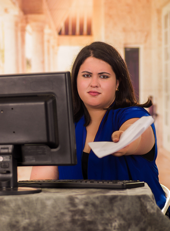 Portrait of fat woman working in the office while sitting in front of her desk in the officeの写真素材