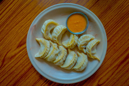 Above view of steamed Momo served in a white plate. A popular Nepalese food that is also common in Chiana, Bhutan, Tibet and India, in a wooden table backgroundの写真素材