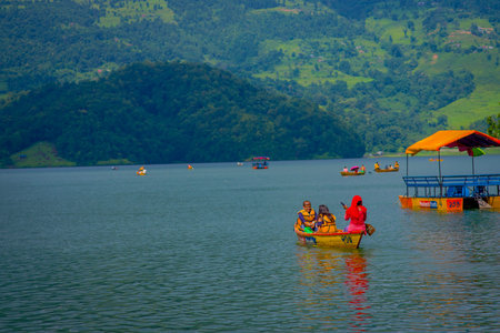 POKHARA, NEPAL - NOVEMBER 04, 2017: Family enjoying of a beautiful day over a yellow boat, neat of a floating structure at Begnas lake in Pokhara, Nepal.のeditorial素材