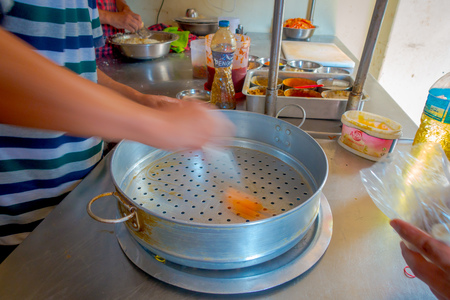 POKHARA, NEPAL OCTOBER 10, 2017: Person cooking a momo food over a metallic tray in the kitchen, type of South Asian dumpling native to Tibet, Nepal, Bhutan and Sikkim in Nepal.のeditorial素材