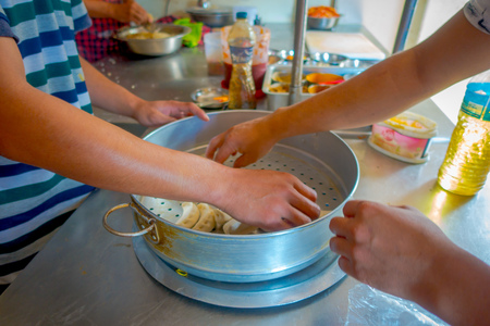 POKHARA, NEPAL OCTOBER 10, 2017: Person cooking a momo food over a metallic tray in the kitchen, type of South Asian dumpling native to Tibet, Nepal, Bhutan and Sikkim in Nepal.のeditorial素材