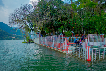 POKHARA, NEPAL - SEPTEMBER 04, 2017: Unidentified people sitting in the lakeshore covered with some metallic structure to protect the people do not fall into the water in Phewa tal-lake in Pokhara, Nepalのeditorial素材