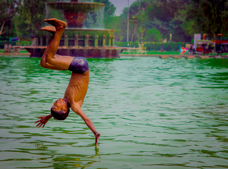 Vrindavan, Uttar Pradesh, India - July 15, 2008 - Three local boys all set to jump in the pond for swimming, one boy already jumped into. Temples showing beside the pond.のeditorial素材