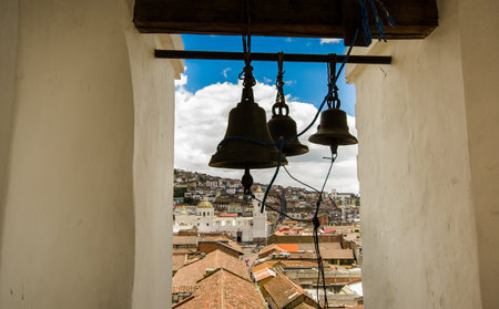 QUITO, ECUADOR - MAY 06 2016: Close up of three huge bells inside of a bulding in the San Francis church, with a town buildings behind in the city of Quitoのeditorial素材