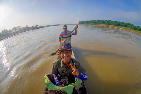 CHITWAN, NEPAL - NOVEMBER 03, 2017: Unidentified people canoeing on wooden boats Pirogues on the Rapti river, in a beautiful sunny day in Chitwan National Park, Nepal, fish eye effectのeditorial素材