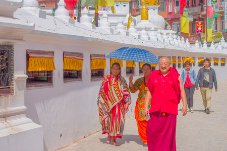 KATHMANDU, NEPAL OCTOBER 15, 2017: Close up of unidentified women walking at outdoors and protecting from the sun using the umbrella, and happy monk walking and wearing typical clothes, close to the monument Boudhanath stupa in Kathmandu, Nepalのeditorial素材