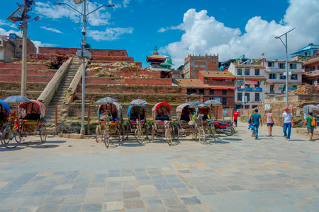KATHMANDU, NEPAL OCTOBER 15, 2017: Rickshaws parked in empy Durbar square with some tourists near...