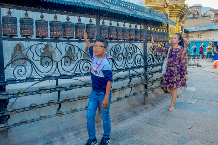 KATHMANDU, NEPAL OCTOBER 15, 2017: Unidentified people walking at outdoors close to Nepalese religious carvings and prayer wheels at Swayambhu Temple also known as the Monkey Temple in Kathmandu, Nepalのeditorial素材
