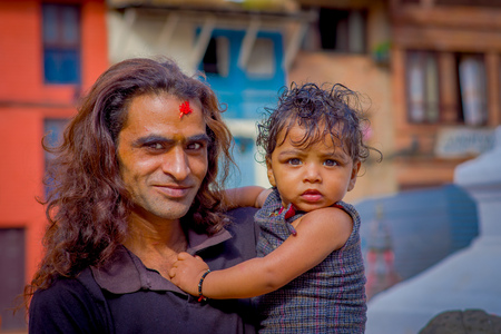 KATHMANDU, NEPAL OCTOBER 15, 2017: Close up of unidentified man holding in his arms his daugher at outside of Durbar Square, Kathmandu, Nepalのeditorial素材
