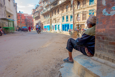 KATHMANDU, NEPAL OCTOBER 15, 2017: Unidentified man sitting at outdoors in a town with very old and damaged building after the earthquake in 2015 of Durbar square in Kathmandu, capital of Nepalのeditorial素材