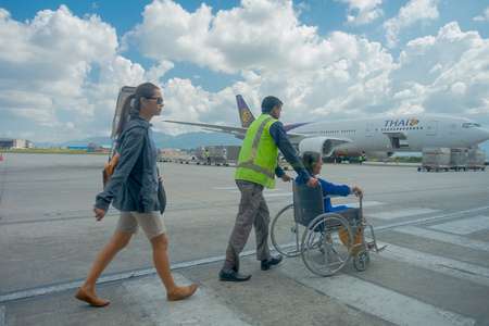 Kathmandu, Nepal, November 16, 2017: Unidentified woman walking and other woman in a wheel chair with an assitant help, boarding their fligh in Kathmandu Airport, Nepalのeditorial素材