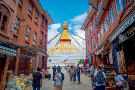 KATHMANDU, NEPAL OCTOBER 15, 2017: Unidentified people walking in the streets between some buildings and enjoying the beautiful monument of Boudhanath stupa and its colorful flags in daylight with bue sky, in Kathmandu, Nepalのeditorial素材
