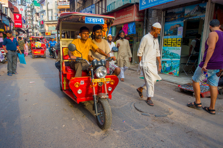 DELHI, INDIA - SEPTEMBER 25 2017: Unidentified people walking in a dirty street in Paharganj, Delhi with a red Rickshaws and an auto-rickshaws. Delhi is the 2nd most populous city in India after Mumbaiのeditorial素材