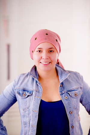 Close up of a woman with cancer wearing headscarf, having positive attitude, in a blurred backgroundの写真素材