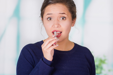 Close up of surprise beautiful woman doing miss lip with pink lipstick in a blurred backgroundの写真素材