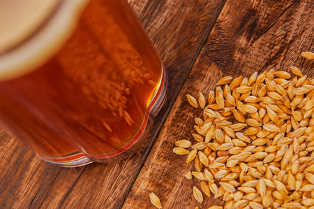 Close up of glass of beer with wheat in the base on a wooden tableの写真素材