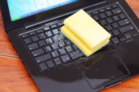 Close up of laptop with water drop damage liquid wet and spill on keyboard and using a yellow sponge...