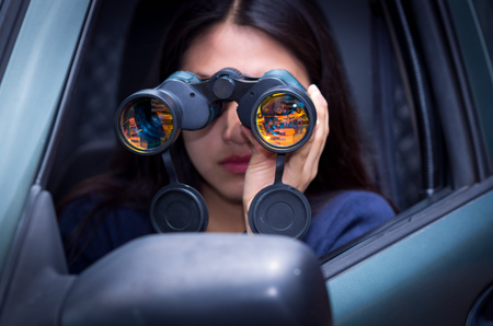 Young woman stalking with a black binoculars inside of her carの写真素材