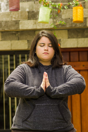 Close up of fat concentrating woman doing yoga exercise at outdoors, with both hands doing a pose,...