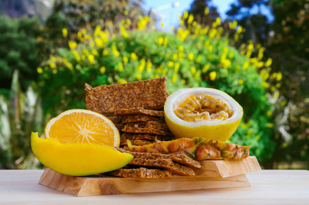 Outdoor view of granola bars with cereals over a wooden table, orange and passion fruit on blurred nature backgroundの写真素材