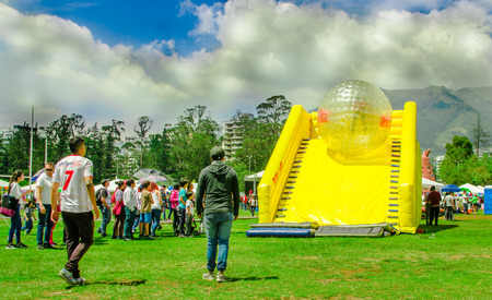 QUITO, ECUADOR - NOVEMBER 28, 2017: Outdoor view of unidentified young people inside of giant inflatable transparent ball sliding in a yellow plastic slide in the Carolina Park during a festival in the city of Quitoのeditorial素材