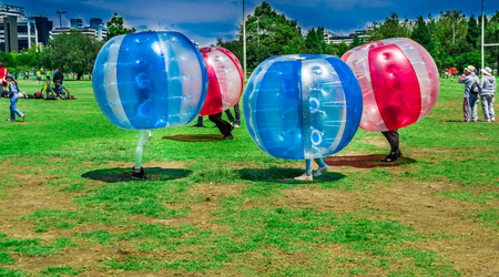 QUITO, ECUADOR - NOVEMBER 28, 2017: Outdoor view of unidentified young people playing soccer while is inside of giant inflatable red and blue balls in the Carolina Park during a festival in the city of Quitoのeditorial素材