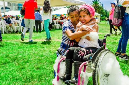 QUITO, ECUADOR- NOVEMBER, 28, 2017: Close up of two chilldren, little girl in a wheel chair covered with foam, true happiness at a foam party at Quito festival in a sunny dayのeditorial素材