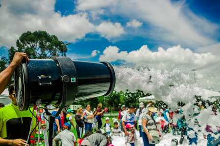 QUITO, ECUADOR- NOVEMBER, 28, 2017: Outdoor view of man shooting foam with a machine and unidentified people enjoying and dancing at a foam party at Quito festivalのeditorial素材