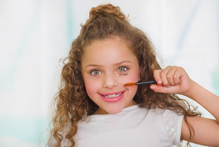 Close up of little girl using wrong an eye mascara in her face in a blurred backgroundの写真素材