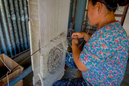 POKHARA, NEPAL - OCTOBER 06 2017: Close up of unidentified woman working on loom manufacturing wool shawl clothing in Nepalのeditorial素材