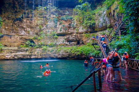 CHICHEN ITZA, MEXICO - NOVEMBER 12, 2017: Unidentified people taking pictures at beautiful Ik-Kil Cenote pond with many people swimming, near Chichen Itza in Mexicoのeditorial素材