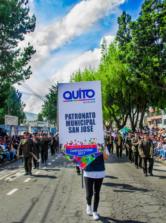 Quito, Ecuador - January 31, 2018: Close up of unidentifed woman holding an informative sign with a group of musicians walking with different instruments behind, during a festival parade in Quito, Ecuadorのeditorial素材