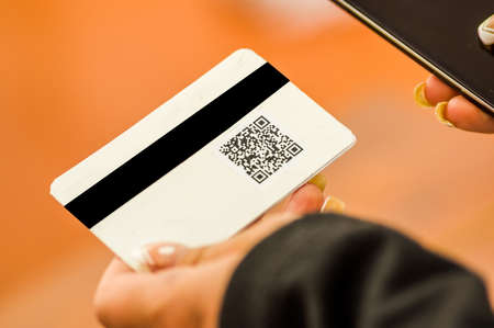Close up of a woman s hand showing business card with QR code information in a blurred backgroundの写真素材