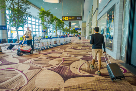 SINGAPORE, SINGAPORE - JANUARY 30, 2018: Unidentified people walking close to a waiting lounge area with some colorful sofas inside of Changi international airportのeditorial素材