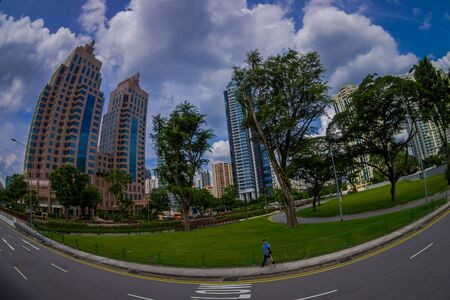 SINGAPORE, SINGAPORE - JANUARY 30. 2018: Beautiful outdoor view of unidentified people walking in a park with a residential condominium building complex in downtown behind in Singapore, fish eye effectのeditorial素材