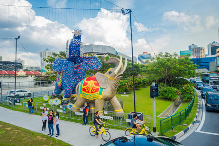 SINGAPORE, SINGAPORE - FEBRUARY 01, 2018: Outdoor view of unidentified people walking in the streets with some cars and huge stoned colorful elephants located at Little India, in Singaporeのeditorial素材