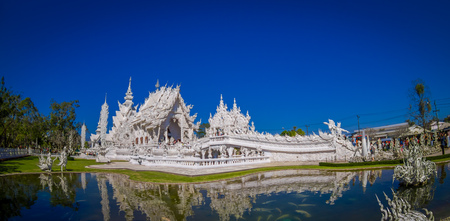 Panoramic view of white church of Wat Rong Khun temple in Chiangrai, Thailand, reflected in the waterの写真素材