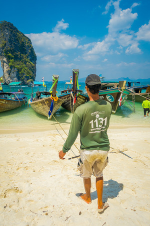 PODA, THAILAND - FEBRUARY 09, 2018: Outdoor view of long tail boats in a row at shore with native people on Poda island in a gorgeous sunny day and turquoise waterのeditorial素材