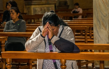 QUITO, ECUADOR, FEBRUARY 22, 2018: Indoor view of unidentified people praying inside of la Catedral church in Quitos Cathedralのeditorial素材