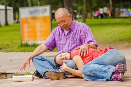 Close up of daughter sleeping in his father legs at outdoors in the parkの写真素材