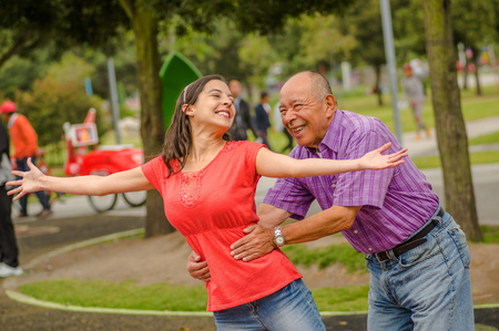 Outdoor view of daughter and father playing at outdoors in the park holding her waistの写真素材