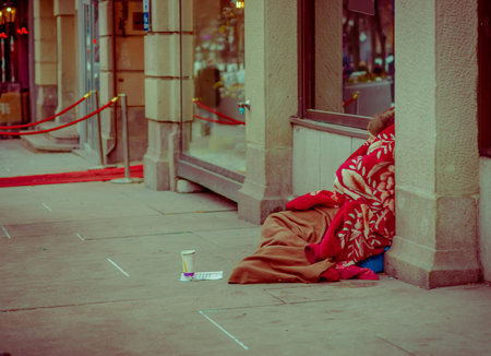 OSLO, NORWAY - MARCH, 26, 2018: Outdoor view of unidentified homeless woman sitting in the ground...