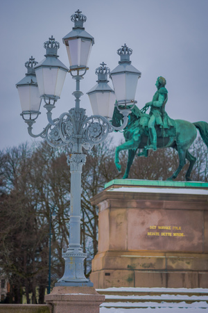 OSLO, NORWAY - MARCH, 26, 2018: Close up of public park lantern with a blurred statue of King Karl Johan behind at the Royal Palace in Osloのeditorial素材